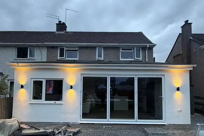 Outdoor wall lights lit on a house at dusk